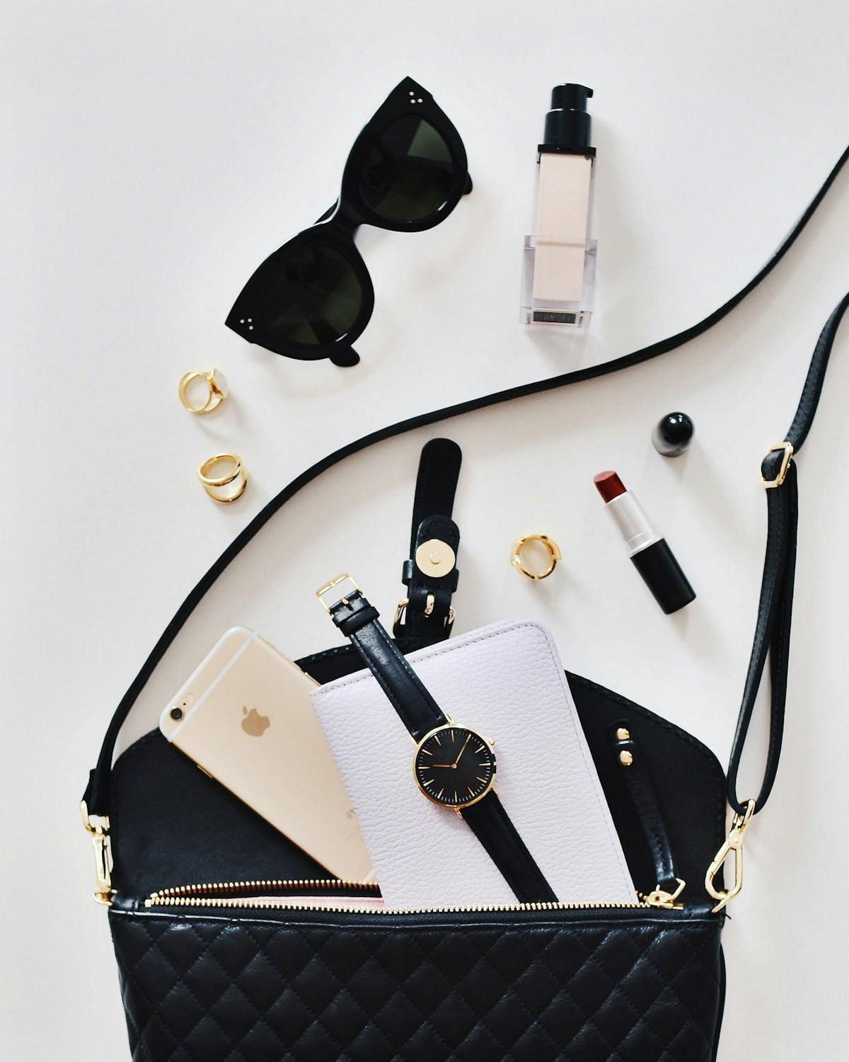 Sunglasses, a watch, and a crossbody bag laid out flat